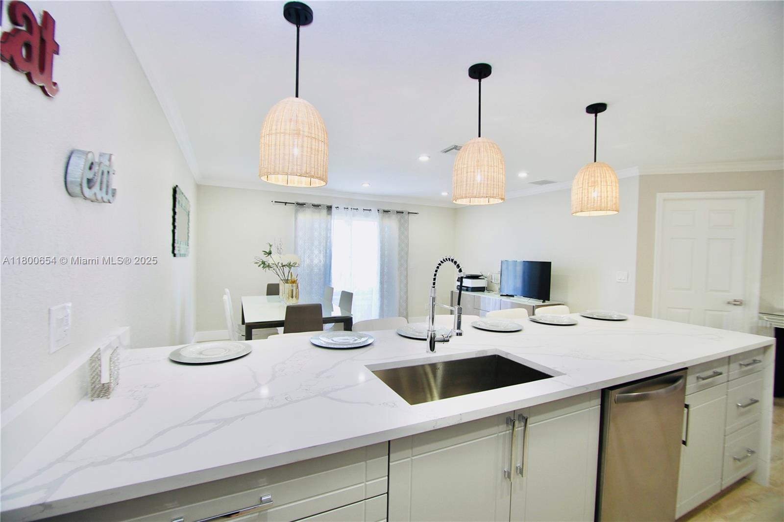 A kitchen island with a white marble countertop and sink sits before a dining area — 244 NW 6th Ave # 244, Delray Beach FL 33444, DELRAY BEACH, FL