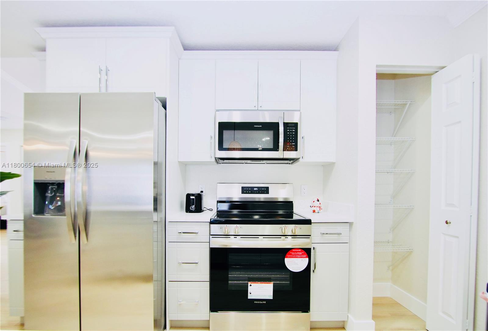 A kitchen features white cabinets, stainless steel appliances, and an adjacent open pantry — 244 NW 6th Ave # 244, Delray Beach FL 33444, DELRAY BEACH, FL
