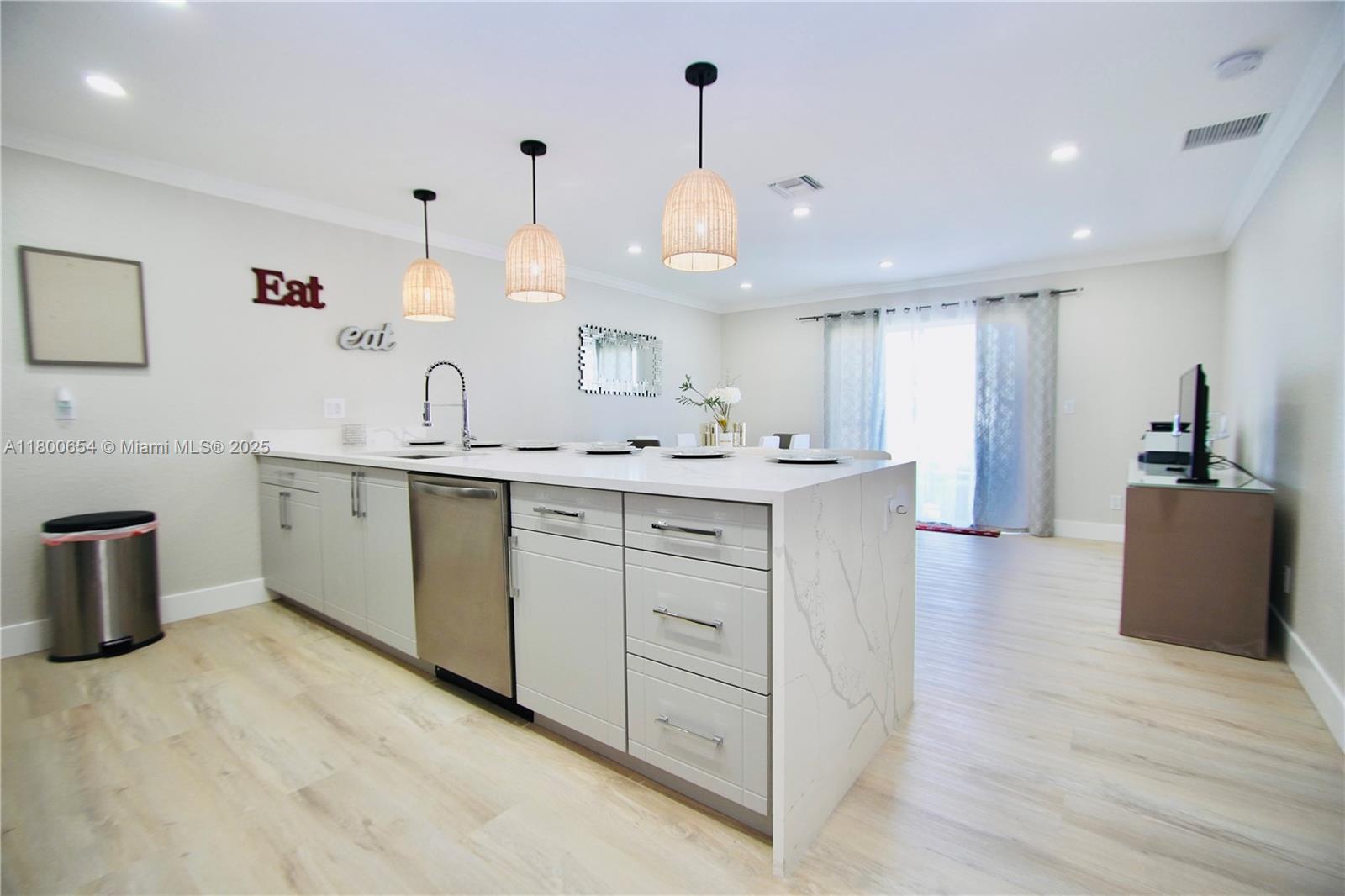 A modern kitchen features a large white quartz island, gray cabinetry, and three pendant lights — 244 NW 6th Ave # 244, Delray Beach FL 33444, DELRAY BEACH, FL