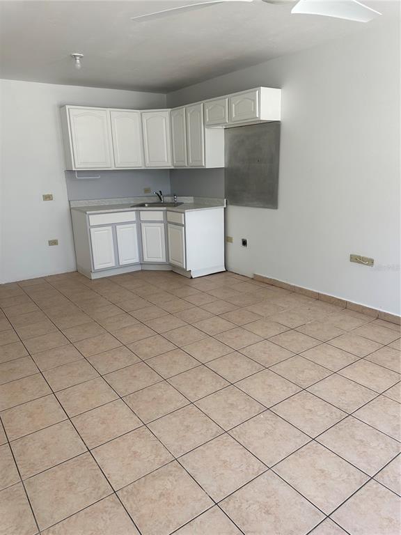 A small kitchen area features white cabinets, a corner sink, and light-colored tile flooring — 2821 CALLE 13, RINCON, PR