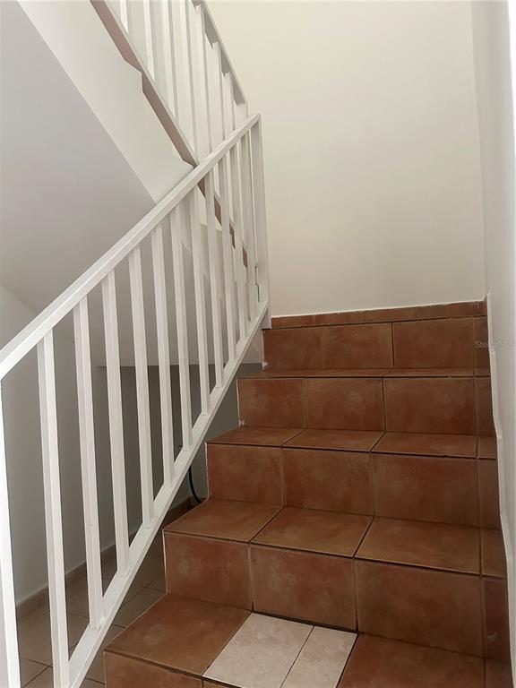 A staircase with terracotta-colored tile steps and a white metal railing leads upward — 2821 CALLE 13, RINCON, PR