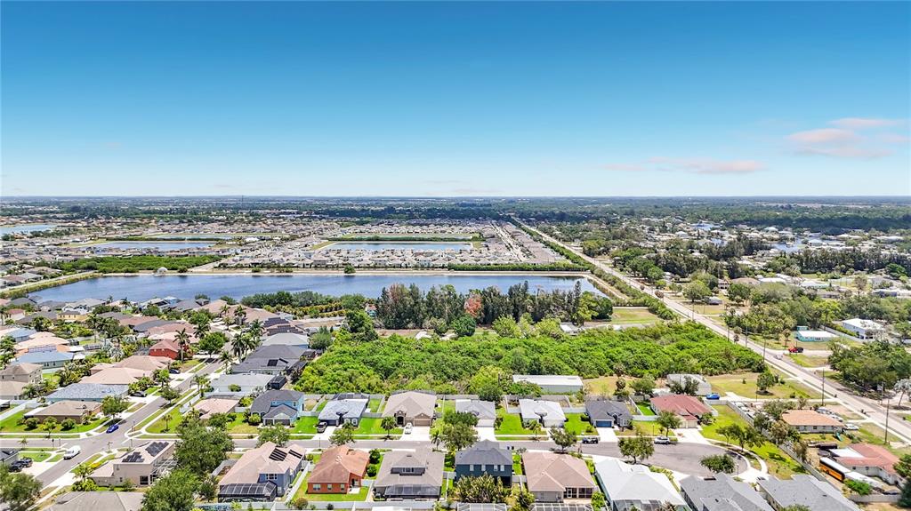 An aerial view shows a residential neighborhood with houses, a large lake, and dense vegetation — 1810 BONITA BLUFF COURT, RUSKIN, FL
