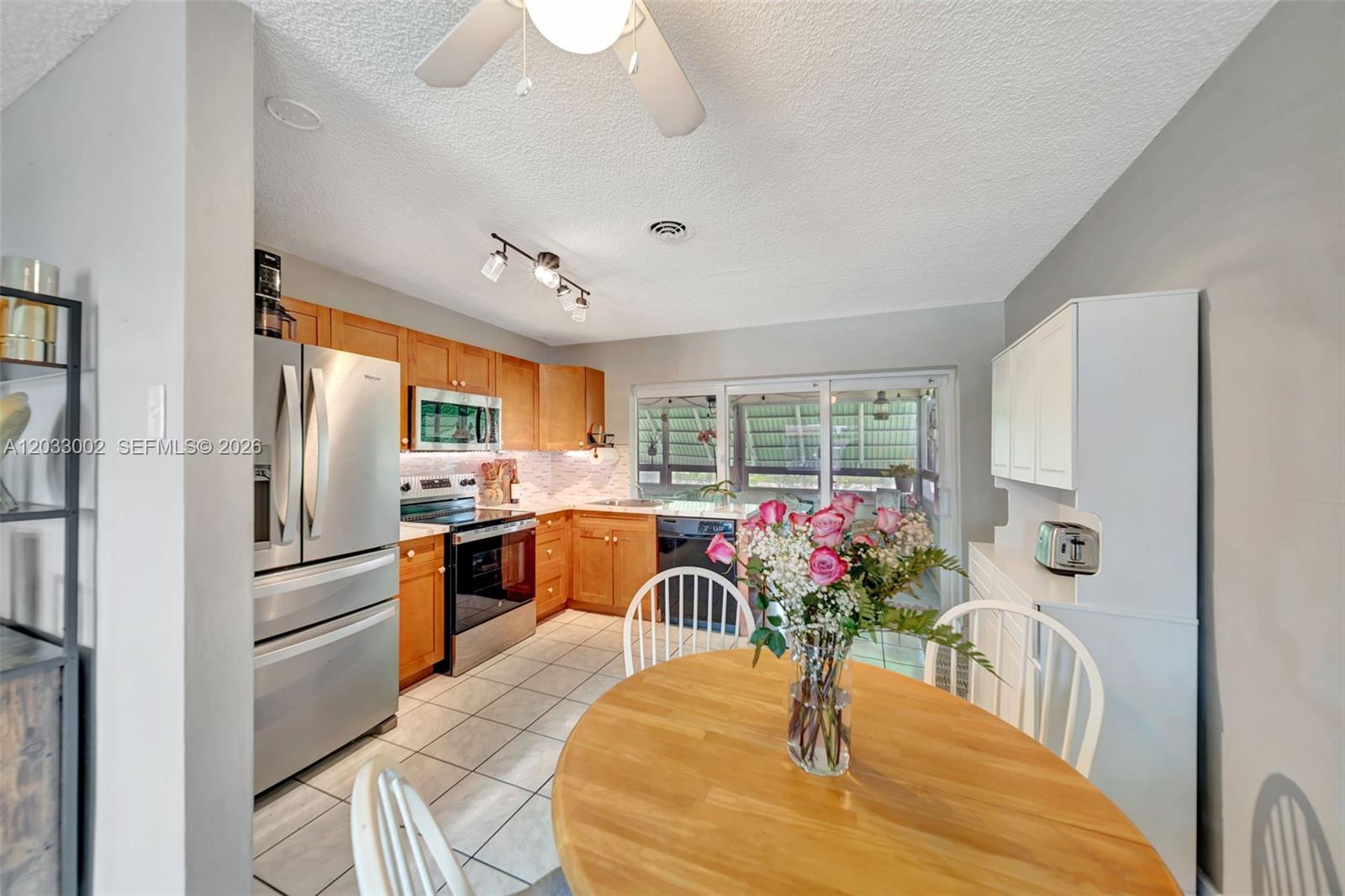 A kitchen with wood cabinets, stainless steel appliances, and a round wooden dining table — 2708 NW 51st Pl, Tamarac FL 33309, TAMARAC, FL