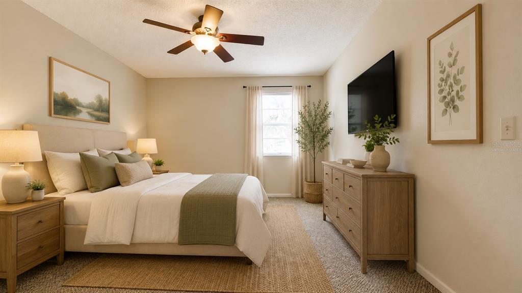 A bedroom features a bed with neutral bedding, a wooden dresser, and a ceiling fan — 3848 59TH AVENUE W, BRADENTON, FL