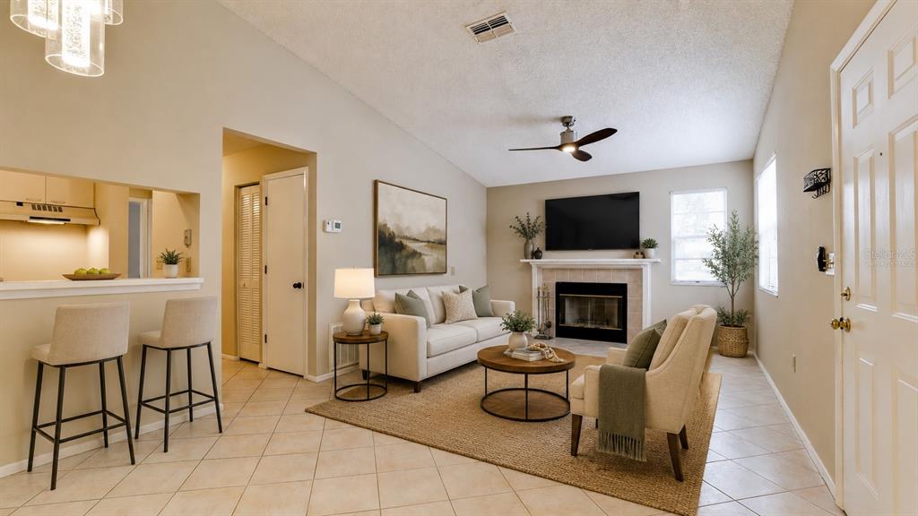 A living room features a fireplace, a sofa, an armchair, and a kitchen breakfast bar — 3848 59TH AVENUE W, BRADENTON, FL