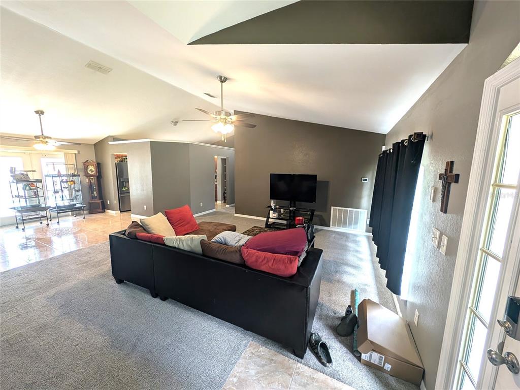 A living room features a dark sectional sofa, a television, and vaulted ceilings — 14968 SW 25TH CIRCLE, OCALA, FL