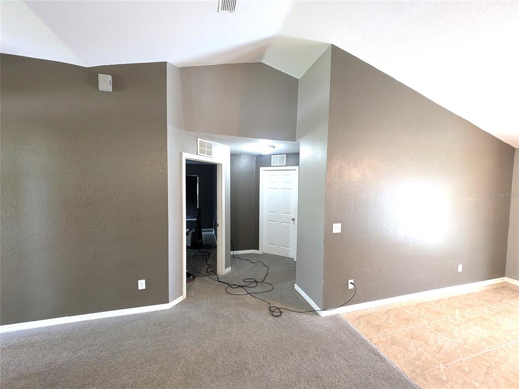 A room with gray walls, carpeted flooring, a tiled area, and two interior doors — 14968 SW 25TH CIRCLE, OCALA, FL