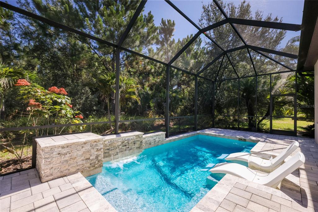 A screened-in patio features a small swimming pool with a stone water feature and loungers — 9728 HIGHLAND PARK PLACE, PALMETTO, FL