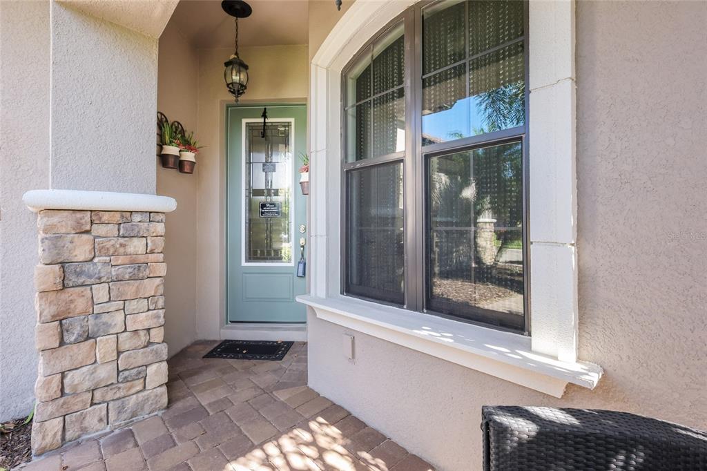 A stone-accented entryway features a light green front door and a large window with trim — 9728 HIGHLAND PARK PLACE, PALMETTO, FL
