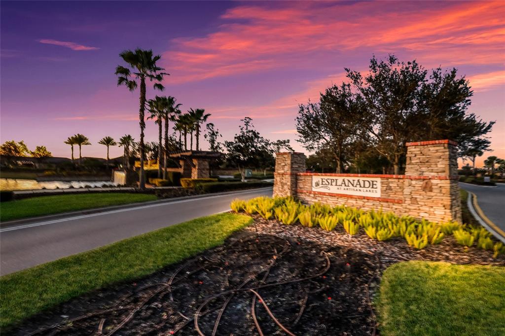 A stone monument sign for Esplanade at Artisan Lakes sits beside a road at sunset — 9728 HIGHLAND PARK PLACE, PALMETTO, FL