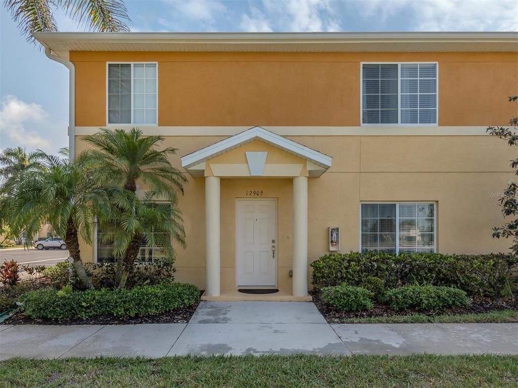 A two-story building exterior features a white front door under a covered entryway — 12905 TIGERS EYE DRIVE, VENICE, FL