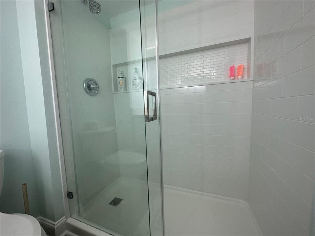 A walk-in shower with a glass door, white subway tile walls, and a recessed niche — 880 MANDALAY AVENUE UNIT S404, CLEARWATER, FL