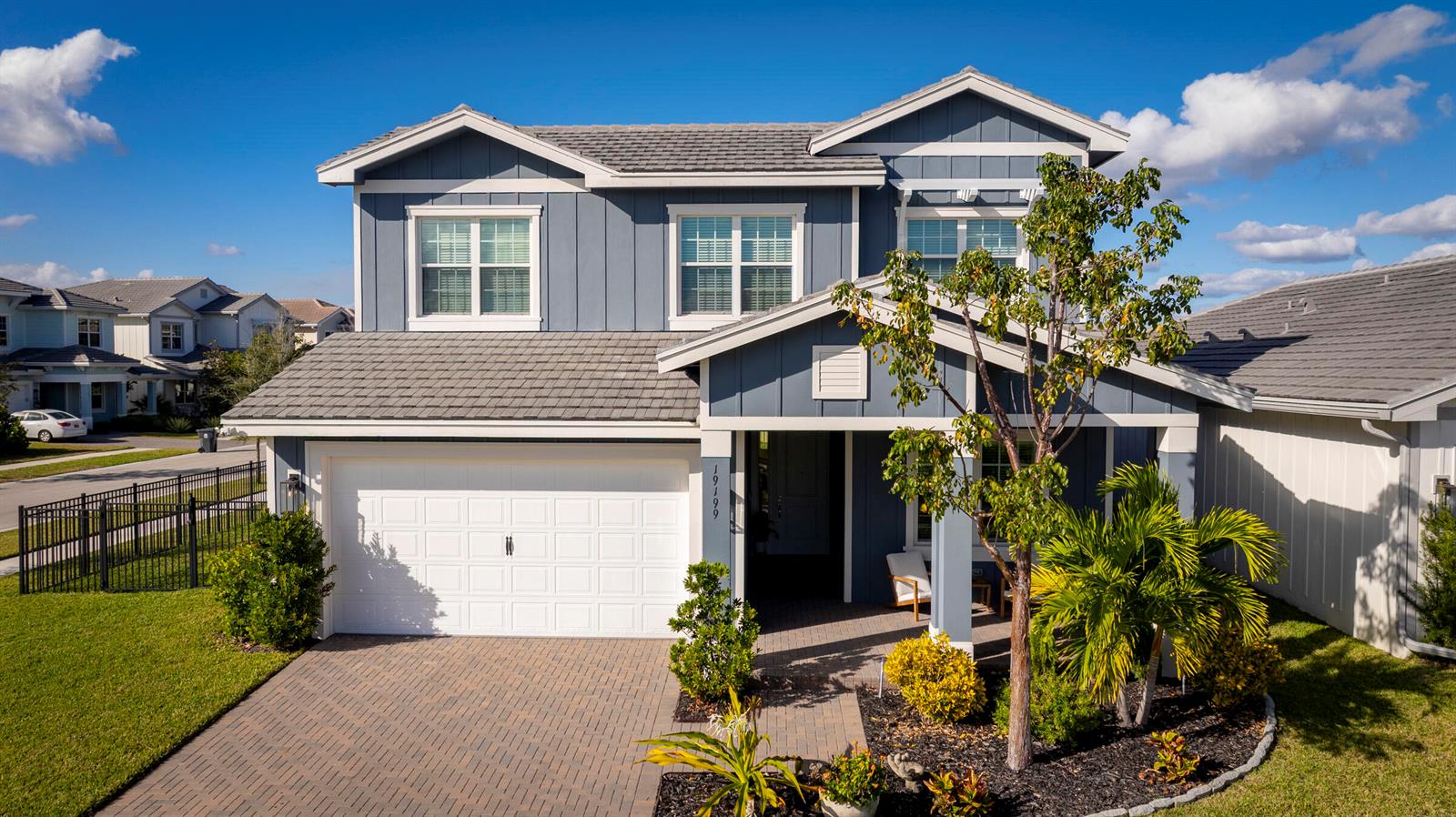 A two-story blue house with a white garage door and a paved driveway — 19199 Rolling Acres Road, FL 33470, FL