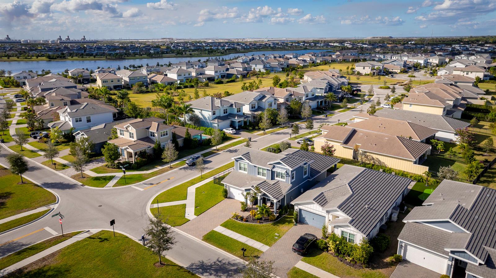 An aerial view shows a suburban neighborhood with many houses, a lake, and streets — 19199 Rolling Acres Road, FL 33470, FL