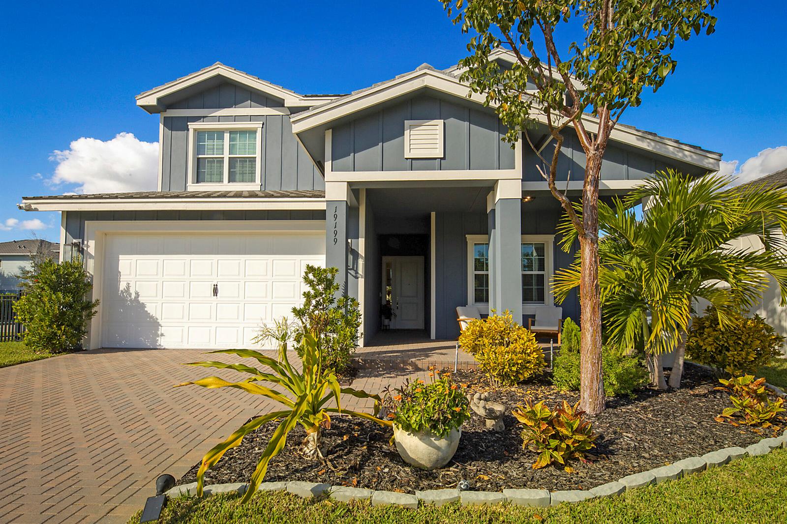 A two-story blue house with a white garage, front porch, and landscaped yard — 19199 Rolling Acres Road, FL 33470, FL
