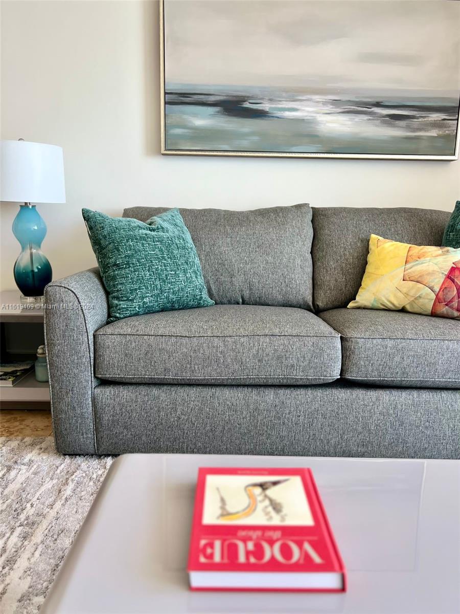 A gray sofa with colorful throw pillows sits in a living room below wall art — 6365 Collins Ave # 2610, Miami Beach FL 33141, MIAMI BEACH, FL