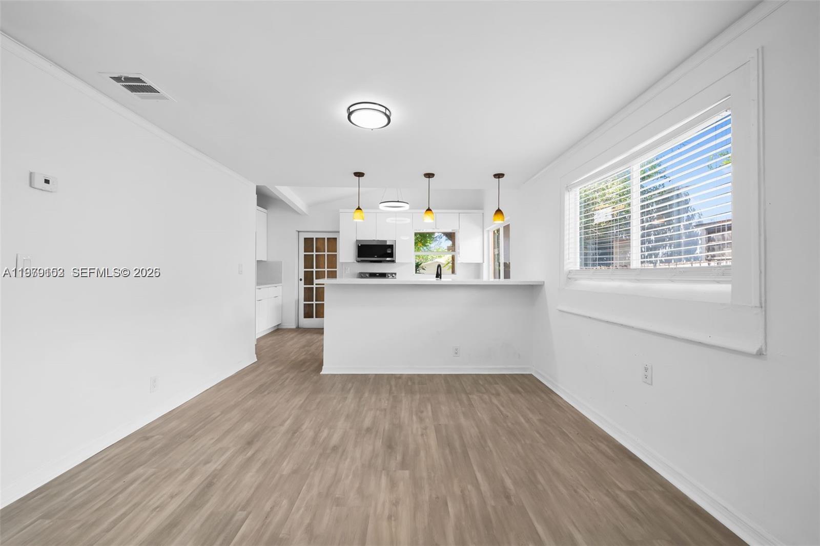 This open-concept dining area features light wood-look flooring and a breakfast bar facing the kitchen — 1640 Funston St, Hollywood FL 33020, HOLLYWOOD, FL
