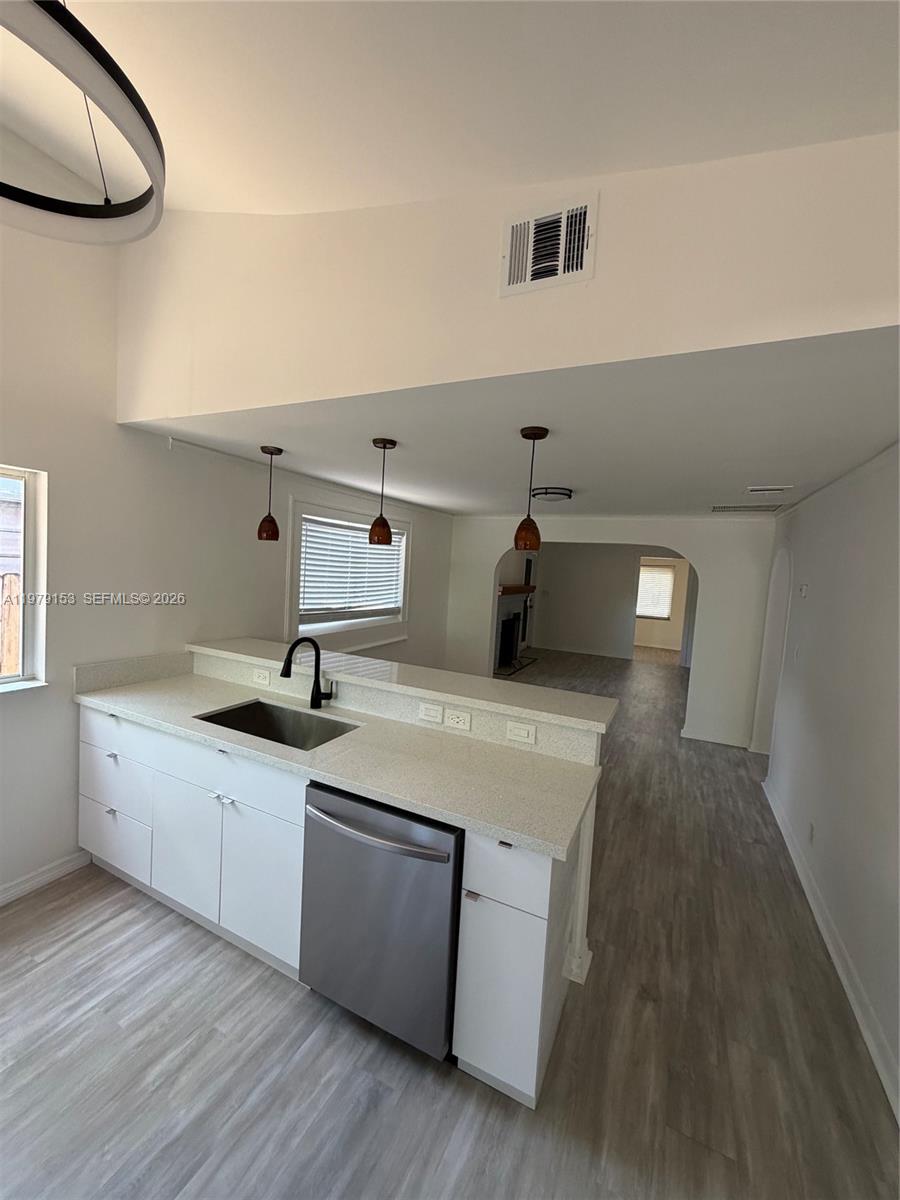 A kitchen with white cabinets, a stainless steel dishwasher, and a light-colored countertop — 1640 Funston St, Hollywood FL 33020, HOLLYWOOD, FL