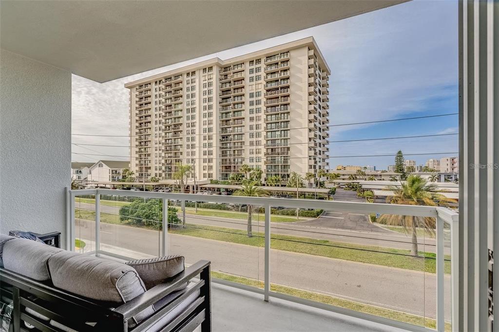 A balcony with a sofa overlooks a street and a large multi-story apartment building — 415 ISLAND WAY UNIT 311, CLEARWATER, FL