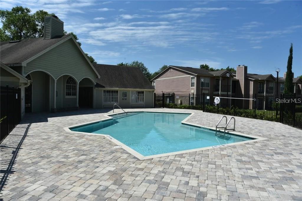 A swimming pool with a paver deck sits in front of a multi-story apartment building — 2550 N ALAFAYA TRAIL UNIT 5203, ORLANDO, FL