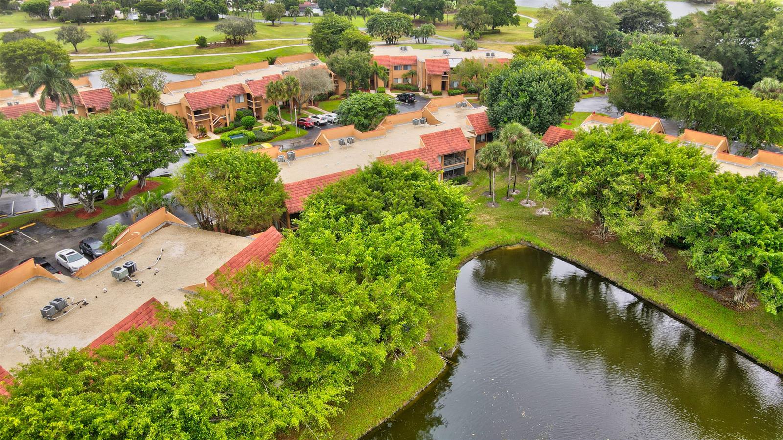 An aerial view of multi-story apartment buildings with red tile roofs surrounded by lush landscaping — 11255 Green Lake Drive # 202, Boynton Beach FL 33437, BOYNTON BEACH, FL
