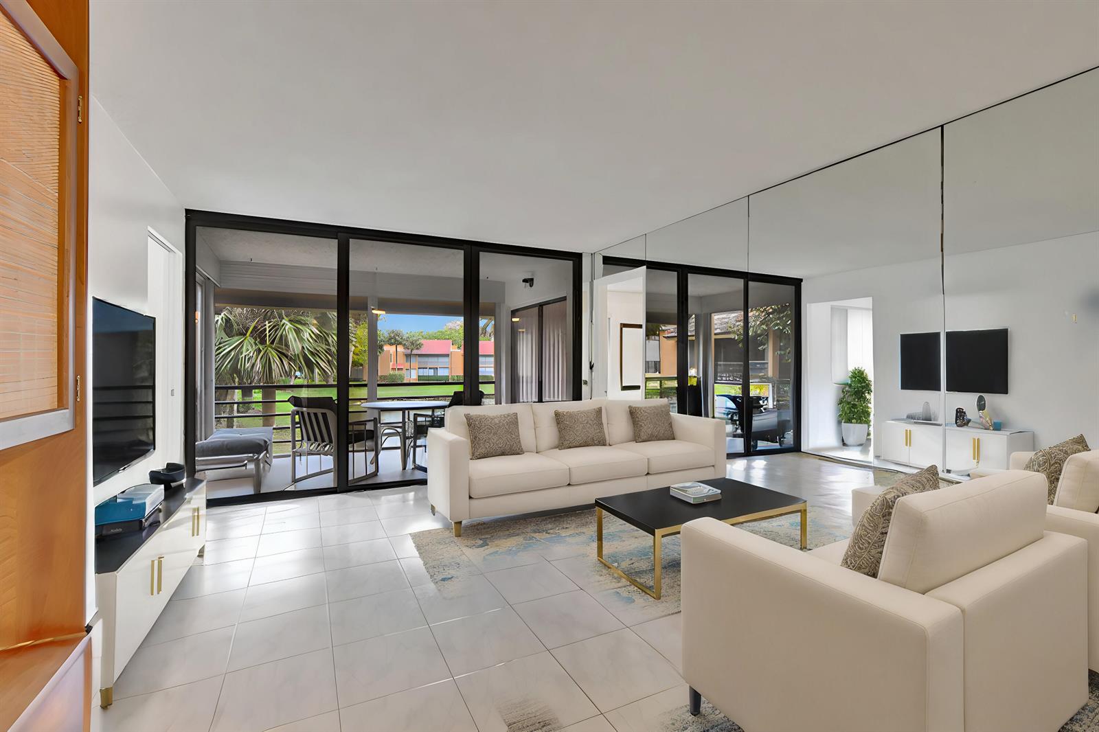 A living room features white tile floors, a white sofa, and a wall of mirrors — 11255 Green Lake Drive # 202, Boynton Beach FL 33437, BOYNTON BEACH, FL