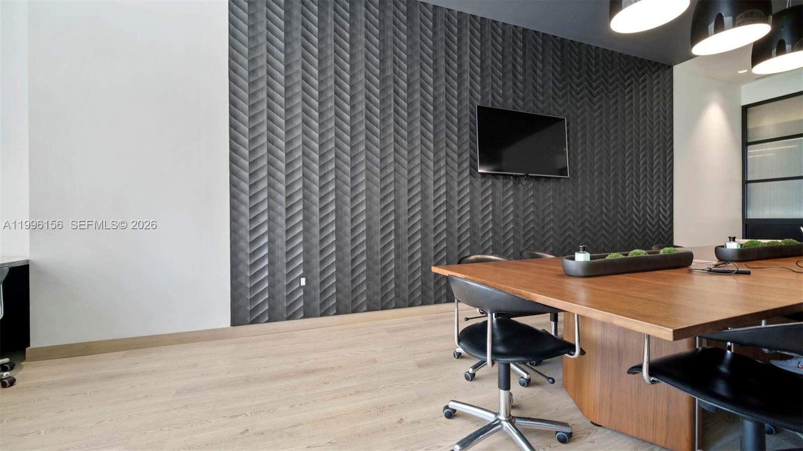 A modern conference room features a textured dark chevron wall, a wooden table, and chairs — 55 SW 9th # 2804, Miami FL 33130, MIAMI, FL