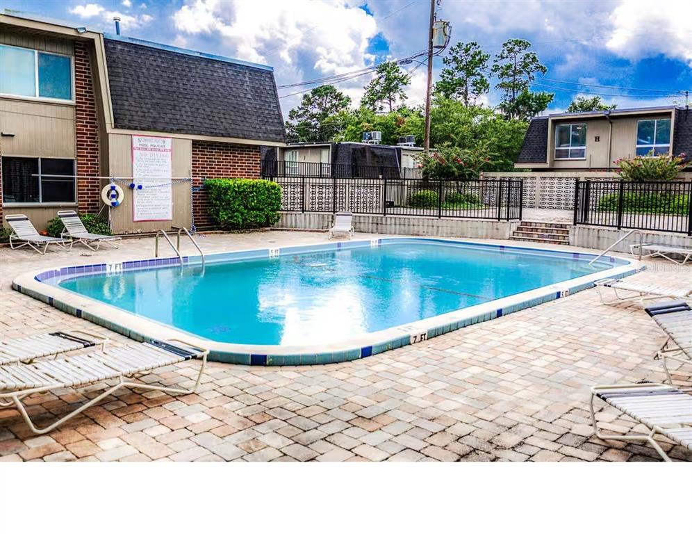 An outdoor swimming pool surrounded by a paved patio and lounge chairs at an apartment complex — 1700 SW 16TH COURT UNIT K24, GAINESVILLE, FL