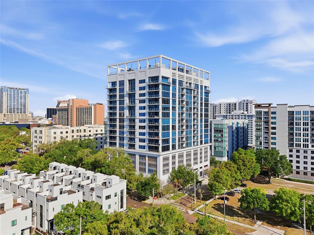 An aerial view shows a modern high-rise apartment building surrounded by trees and urban structures — 260 S OSCEOLA AVENUE UNIT 902, ORLANDO, FL