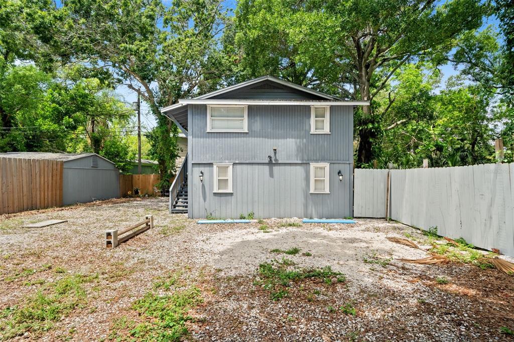 The exterior of a two-story gray house with a gravel yard and wooden fencing — 4834 TAYLOR STREET N, ST PETERSBURG, FL