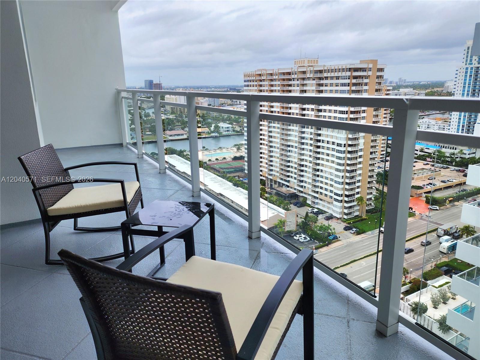 A balcony with two chairs and a small table overlooks a city and waterway — 2030 S Ocean Dr # 2204, Hallandale Beach FL 33009, HALLANDALE BEACH, FL