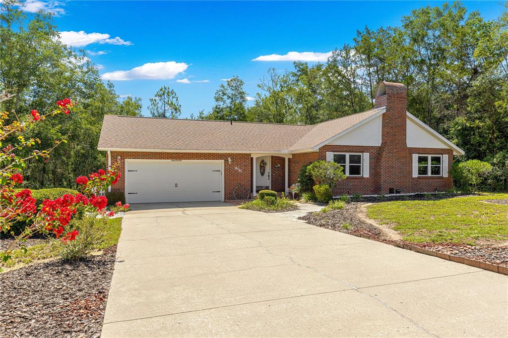 A single-story brick house with a two-car garage, chimney, and a concrete driveway — 9701 SW 200TH COURT, DUNNELLON, FL