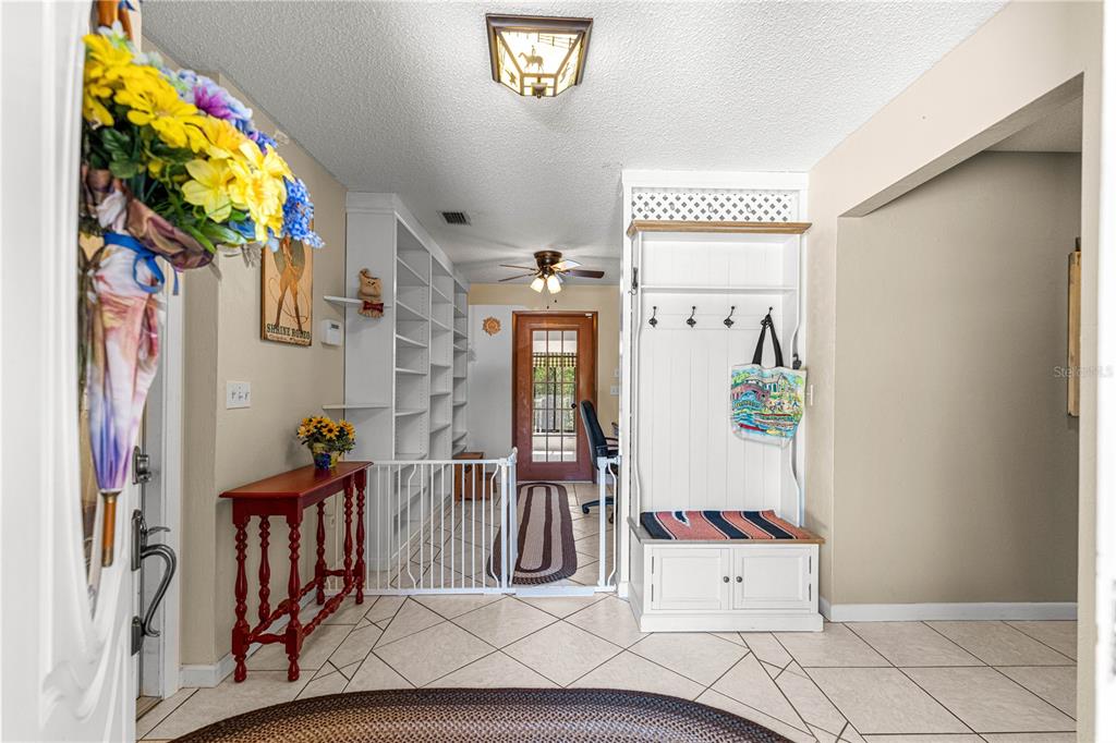 An entryway features tile flooring, a white hall tree, built-in shelving, and a red console table — 9701 SW 200TH COURT, DUNNELLON, FL