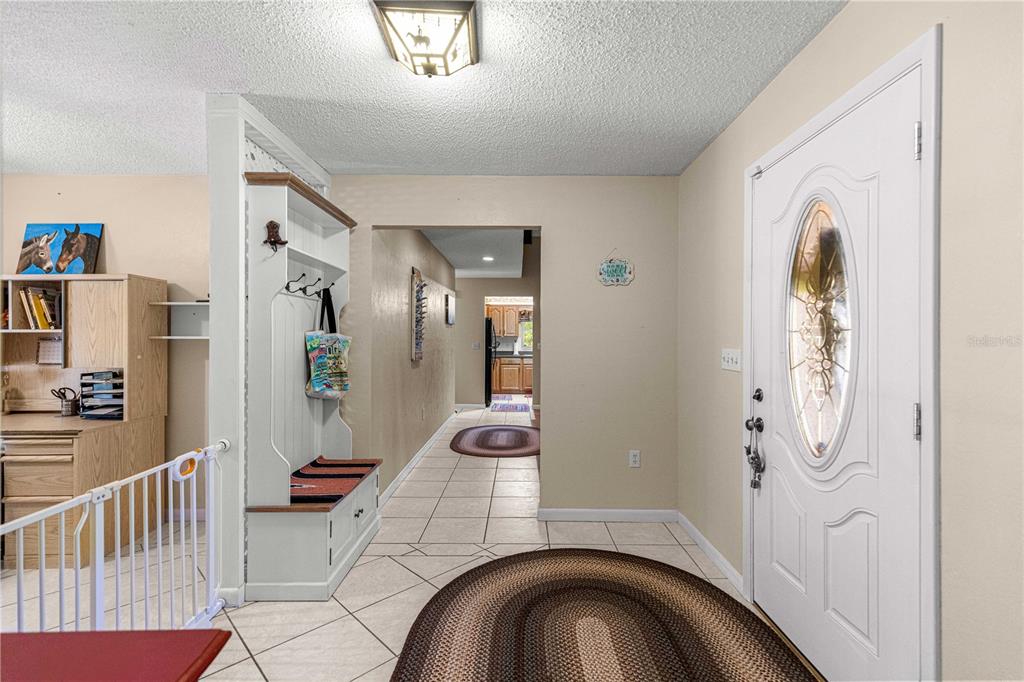 An entryway features a white front door, a coat rack bench, and tile flooring — 9701 SW 200TH COURT, DUNNELLON, FL