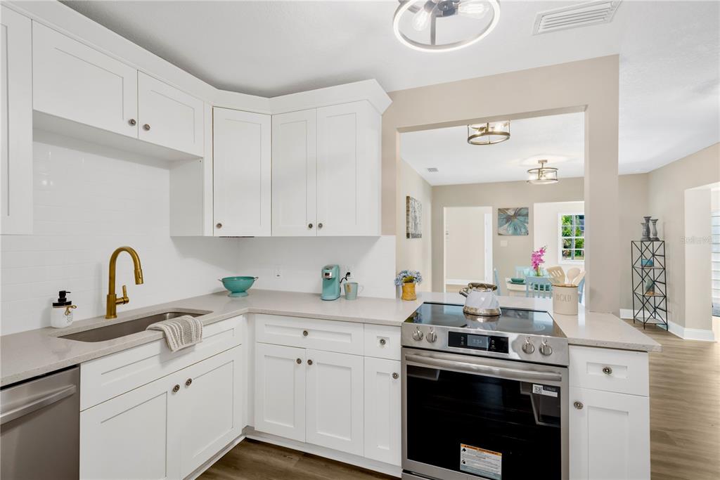 A kitchen features white cabinets, quartz countertops, a stainless steel stove, and a gold faucet — 3903 W PALMETTO STREET, TAMPA, FL