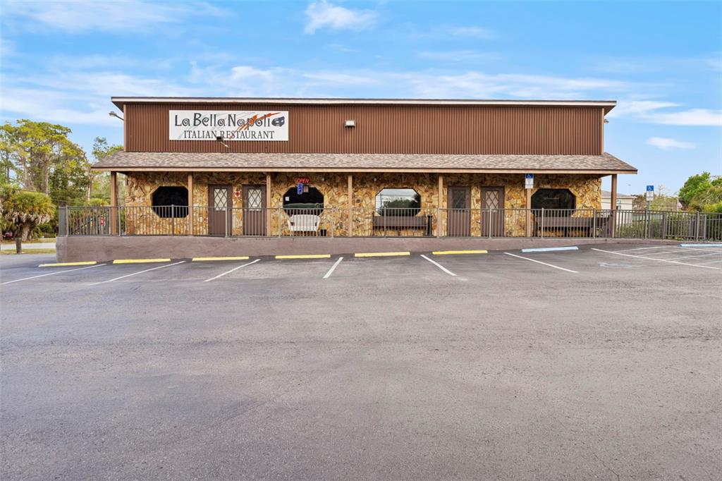 A single-story Italian restaurant building features a stone facade, brown siding, and a parking lot — 7390 SHOAL LINE BOULEVARD, WEEKI WACHEE, FL