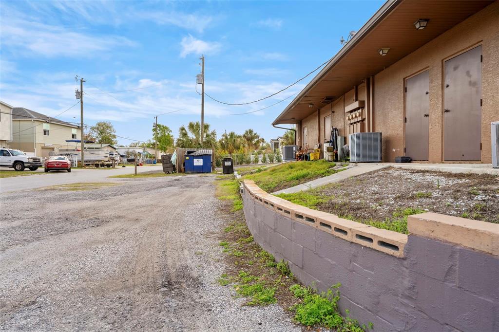 A gravel driveway leads to a building exterior with a low concrete block retaining wall — 7390 SHOAL LINE BOULEVARD, WEEKI WACHEE, FL