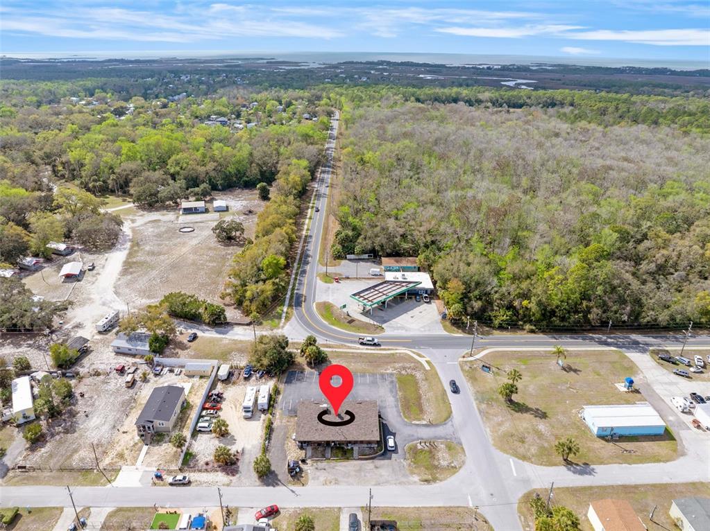 This aerial view shows a commercial building with a parking lot near a gas station — 7390 SHOAL LINE BOULEVARD, WEEKI WACHEE, FL