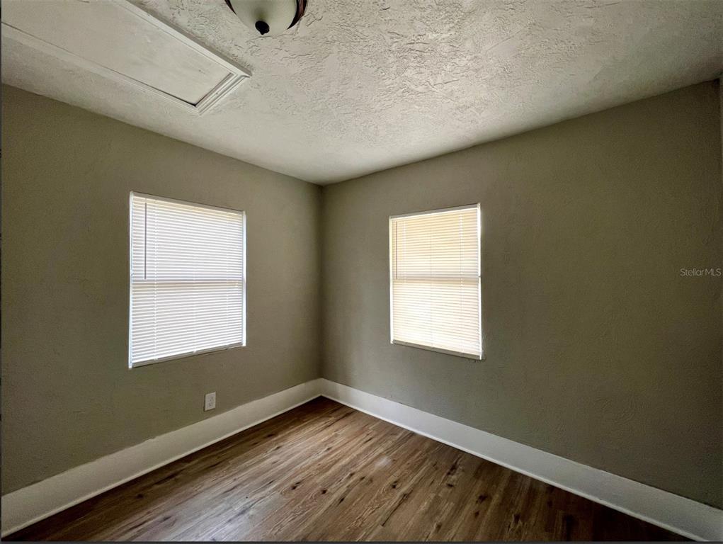 An empty room with light-colored walls, wood-look flooring, white trim, and two windows with blinds — 2003 10TH STREET S, ST PETERSBURG, FL