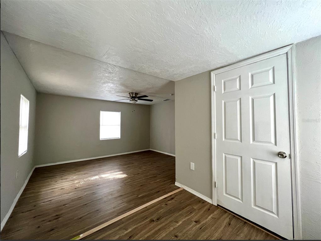An empty room with wood-look flooring, a ceiling fan, and a white six-panel door — 2003 10TH STREET S, ST PETERSBURG, FL