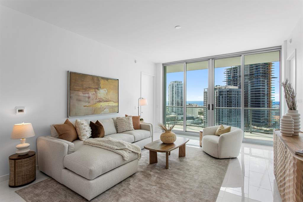 A modern living room with a sectional sofa, area rug, and floor-to-ceiling windows overlooking city buildings — 400 CENTRAL AVENUE UNIT 1704, ST PETERSBURG, FL