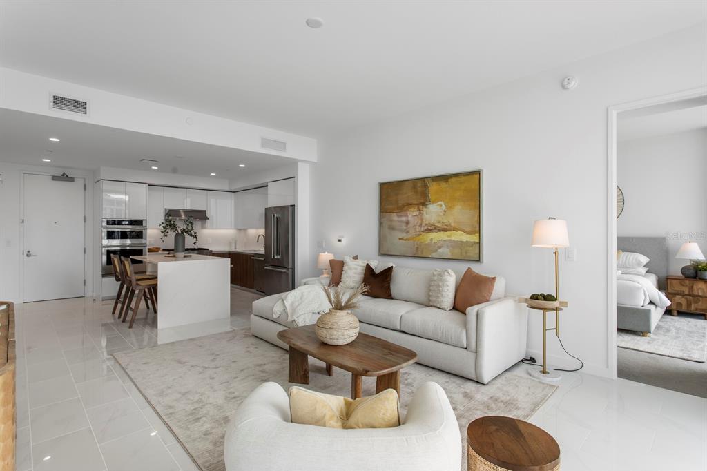 A modern open-concept living room features a white sofa, wooden coffee table, and adjacent kitchen — 400 CENTRAL AVENUE UNIT 1704, ST PETERSBURG, FL