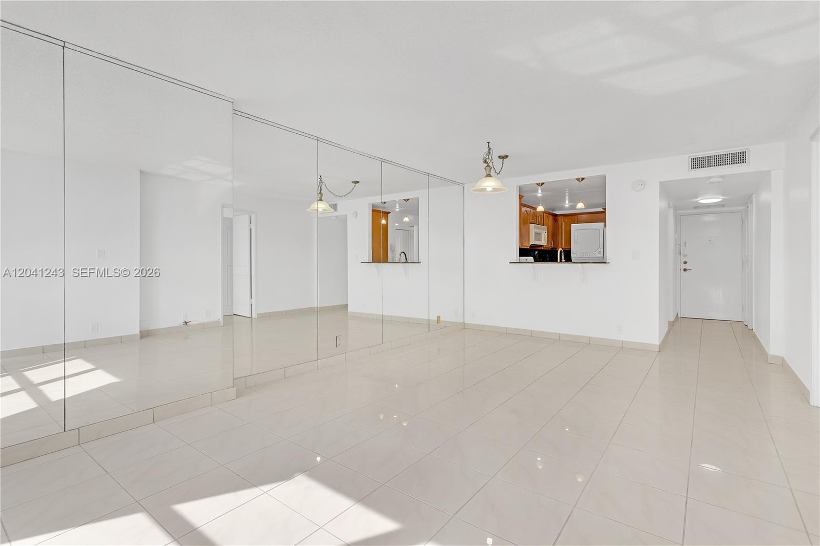 A bright, tiled living area features a large mirrored wall and a kitchen pass-through window — 1865 Brickell Ave # A805, Miami FL 33129, MIAMI, FL