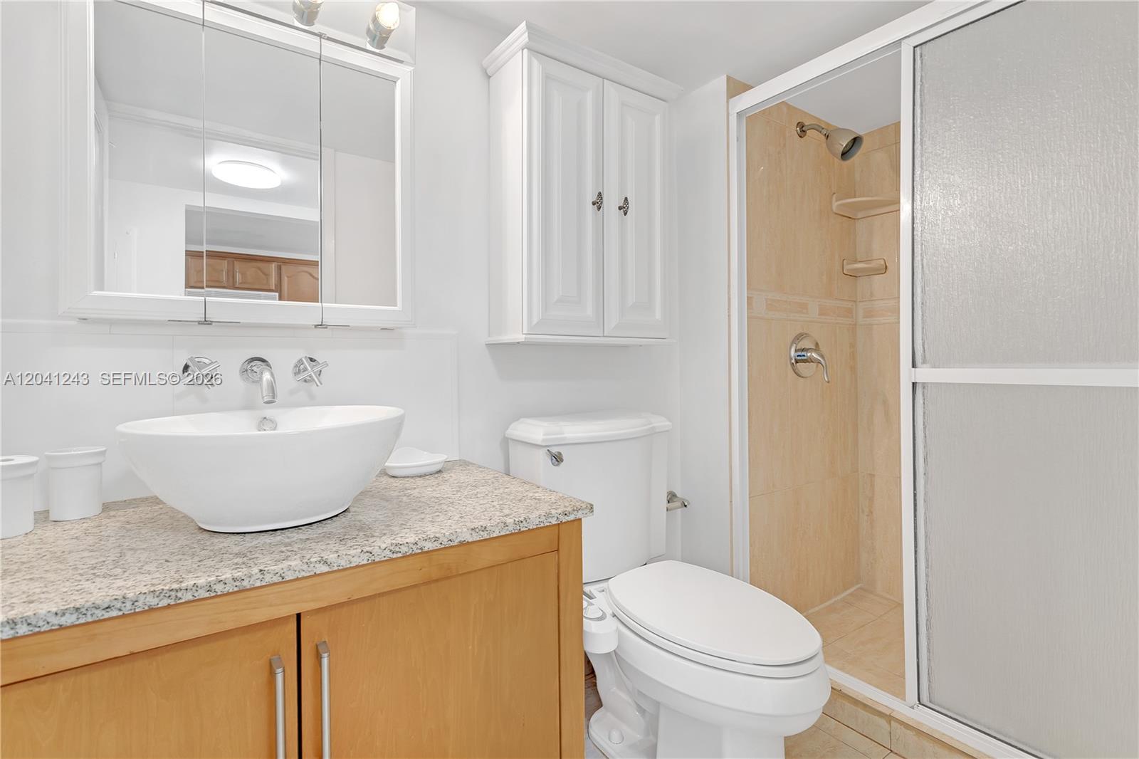 A bathroom features a vessel sink on a granite vanity, a toilet, and a shower — 1865 Brickell Ave # A805, Miami FL 33129, MIAMI, FL