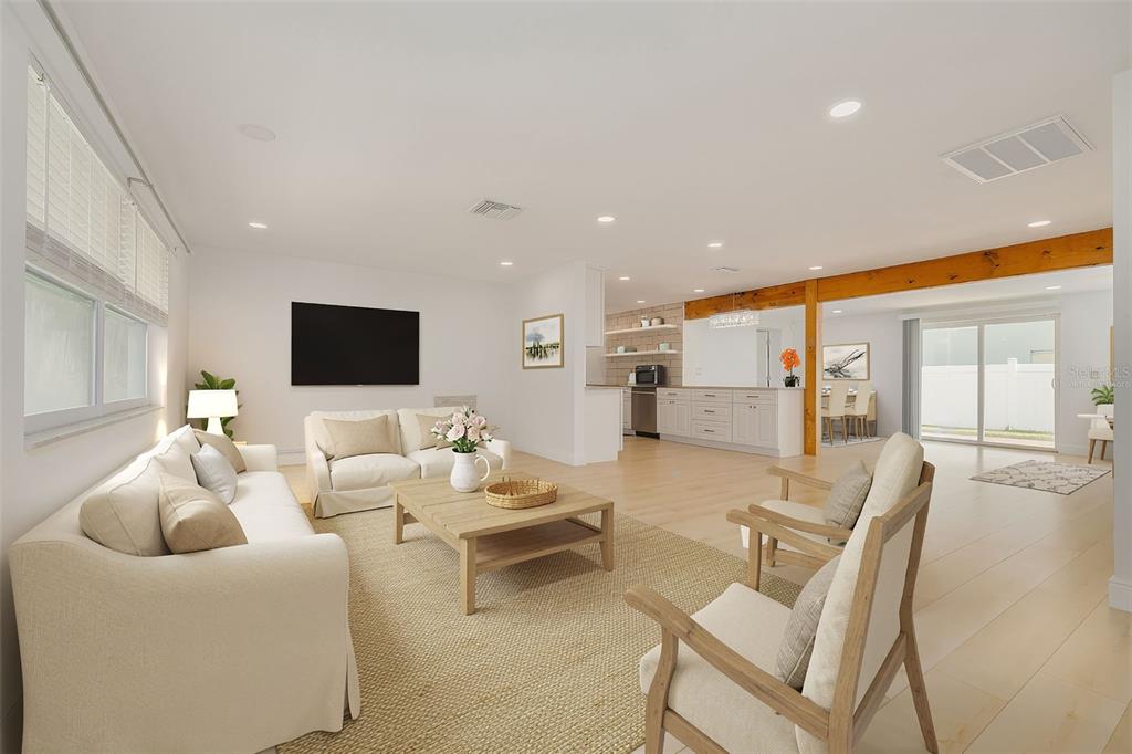 A bright, open-concept living room features light wood flooring, a neutral sofa, and a kitchen — 2631 OAKBROOK DRIVE, LARGO, FL