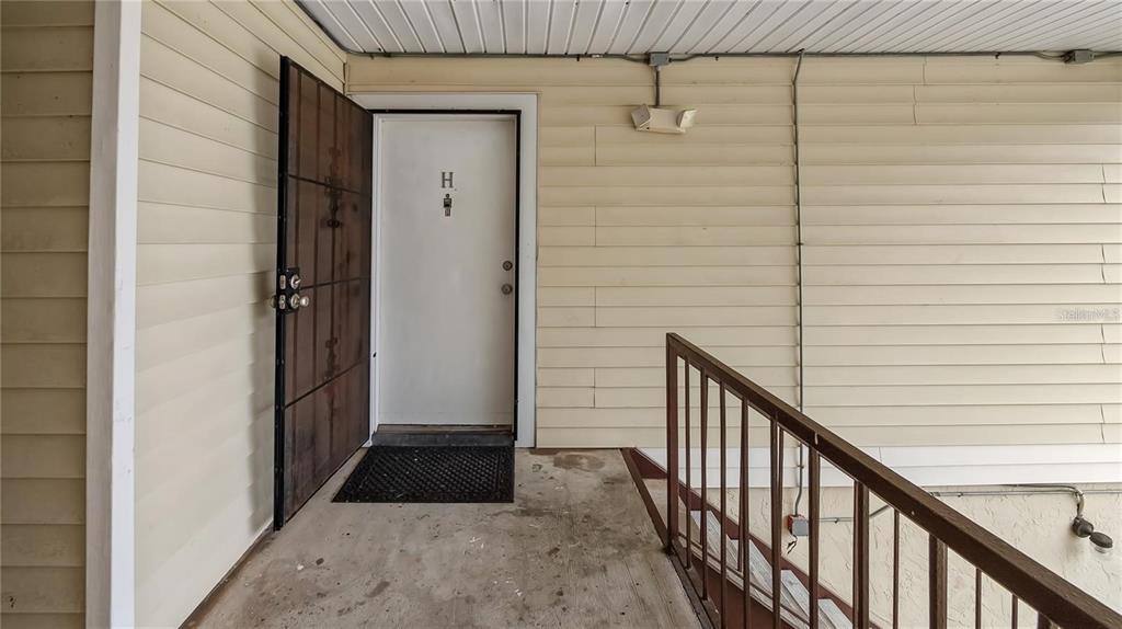 An exterior view of a building entrance with a white door labeled H — 314 CHEROKEE COURT UNIT H, ALTAMONTE SPRINGS, FL