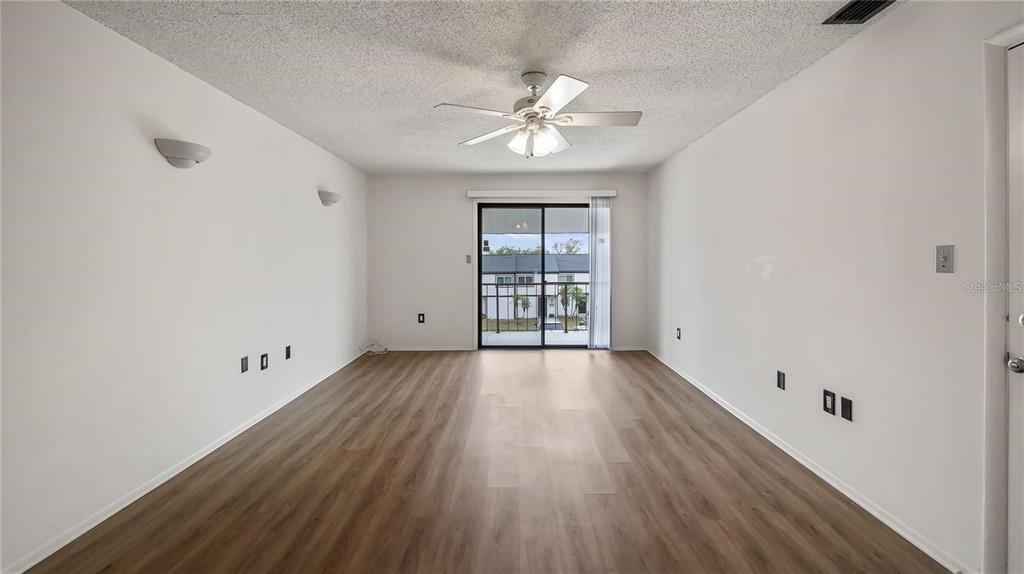 An empty room with wood-look flooring, a ceiling fan, and sliding glass doors to a balcony — 314 CHEROKEE COURT UNIT H, ALTAMONTE SPRINGS, FL