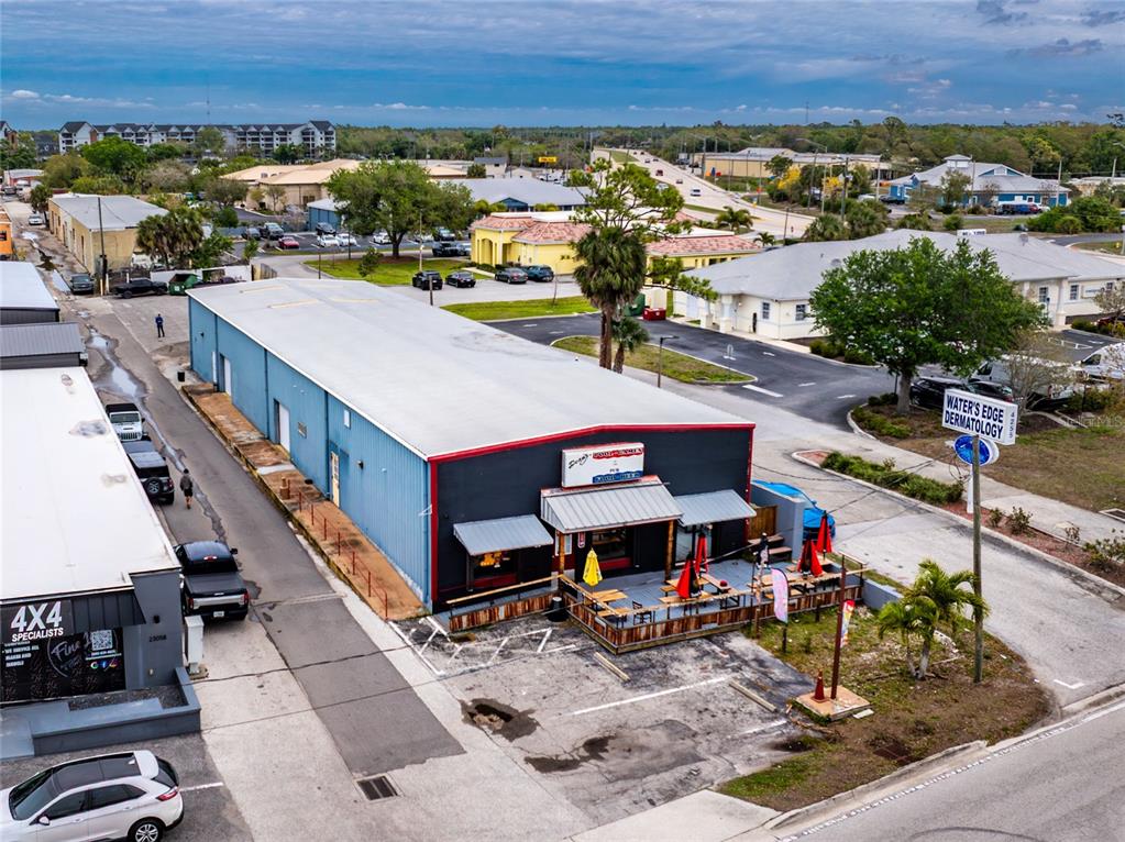 An aerial view shows a commercial building with a patio and adjacent parking lot — 23064 HARBORVIEW ROAD UNIT A and B and C, PORT CHARLOTTE, FL