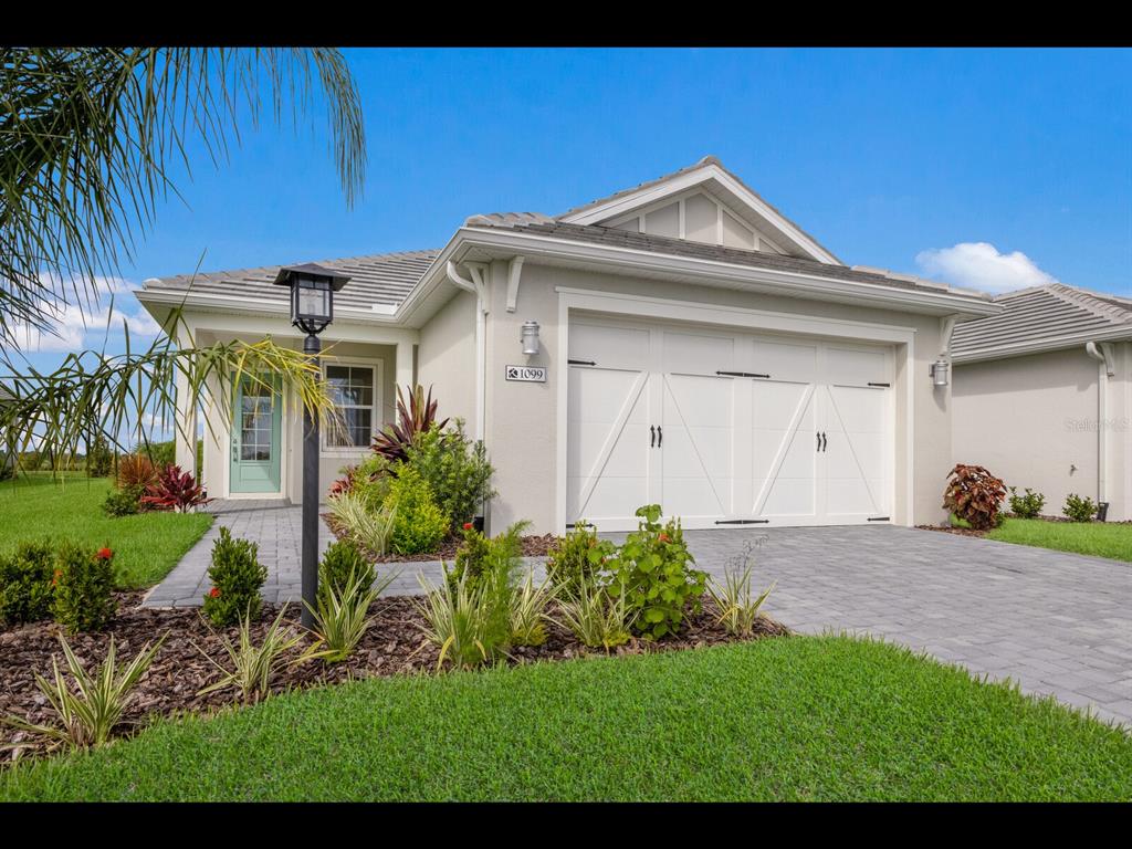 A single-story house with a white garage, light green front door, and landscaped front yard — 1099 WATERLINE COURT, SARASOTA, FL