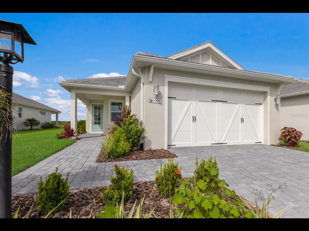 A single-story house with a white garage door, a teal front door, and a paver driveway — 1099 WATERLINE COURT, SARASOTA, FL